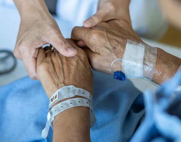 Pflegerin hält die Hände eines Patienten