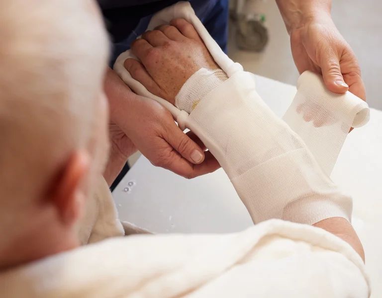 Ärztin legt Gipsverband bei einem Patienten an