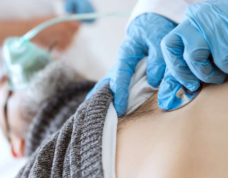 Patient in der Intensivstation, Beatmung und Untersuchung mit dem Stethoskop