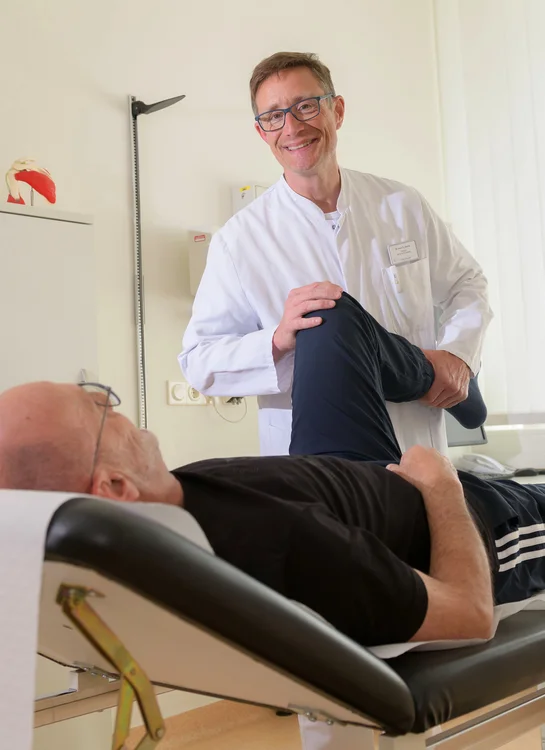 Arzt untersucht das Knie eines Patienten