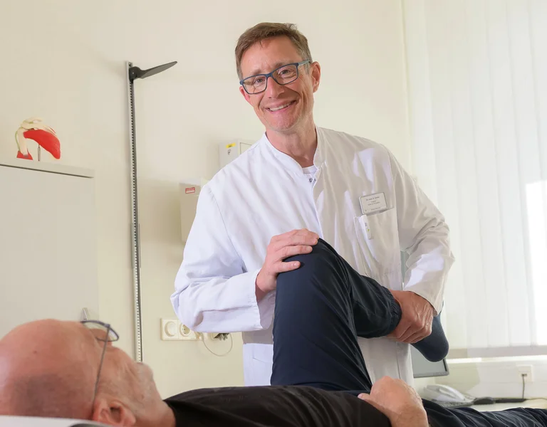 Arzt untersucht das Knie eines Patienten